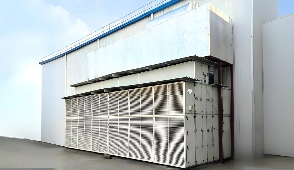 Large industrial HVAC unit installed outside a factory building, featuring multiple ventilation panels and duct connections.